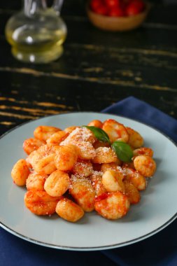 Koyu ahşap masada domates soslu lezzetli gnocchi.