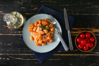 Koyu ahşap arka planda domates soslu lezzetli gnocchi.