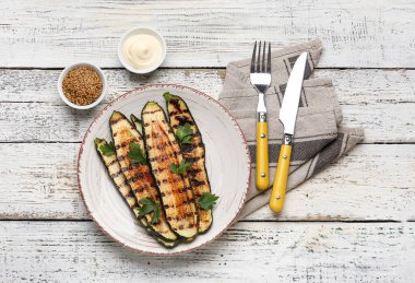 Lezzetli ızgara kabak tabağı ve ahşap arka planda soslu kâseler.