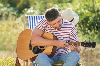 Genç adam yaz günü barbekü partisinde gitar çalıyor.
