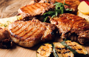 Lezzetli domuz bifteği ve ahşap arka planda ızgara sebzeli pano.