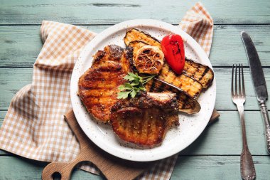 Lezzetli domuz bifteği ve ahşap arka planda ızgara sebze tabağı.