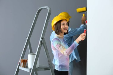 Yeni evinde duvar boyayan genç bir kadın.