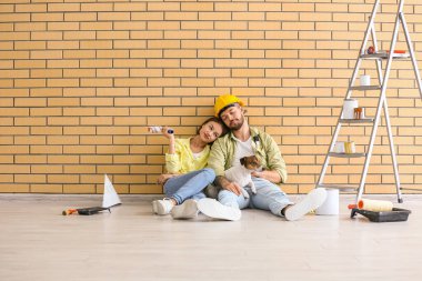 Yeni evlerinde tadilat sırasında şirin köpekleri olan genç bir çift dinleniyor.