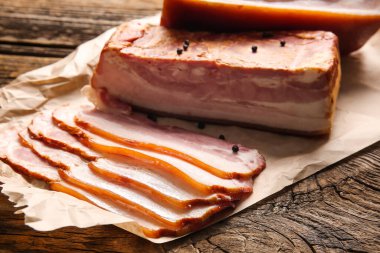 Ahşap arka planda lezzetli tütsülenmiş pastırma dilimleri, yakın plan.