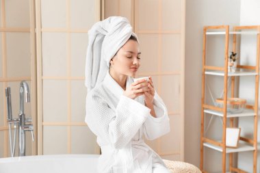 Genç bayan banyoda kahve içiyor.