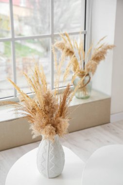 Vase with pampas grass on table in living room clipart