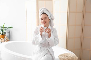 Genç bayan banyoda kahve içiyor.