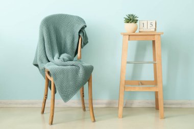 Sandalyeye ve masaya ekose örülmüş, takvimi de renk duvarına yakın.