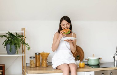 Genç bir kadın mutfakta lezzetli kruvasan yiyor.