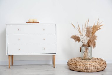 Işık duvarının yanında modern çekmeceler ve vazolar.