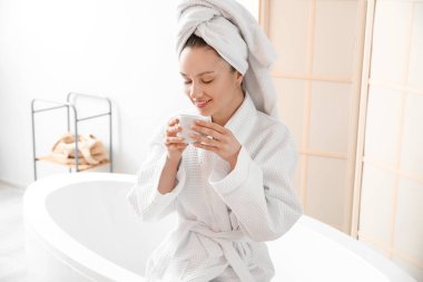 Genç bayan banyoda kahve içiyor.