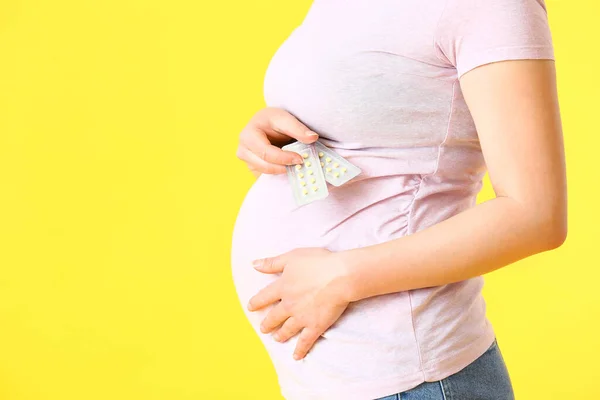 若いです妊娠中の女性とともに丸薬上の色背景 — ストック写真