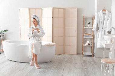 Genç bayan banyoda kahve içiyor.