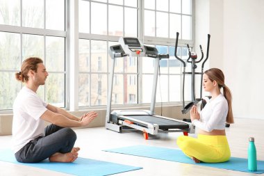 Genç hamile kadın ve kocası spor salonunda yoga yapıyorlar.