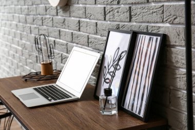Laptoplu modern işyeri ve tuğla duvarın yanındaki resimler.