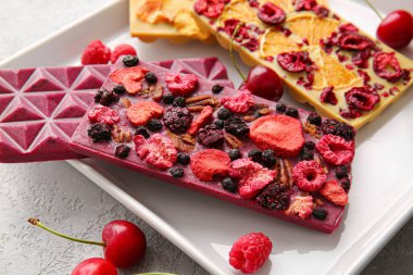 Arka planda meyve, böğürtlen ve fındıklı el yapımı çikolatalar, yakın plan.