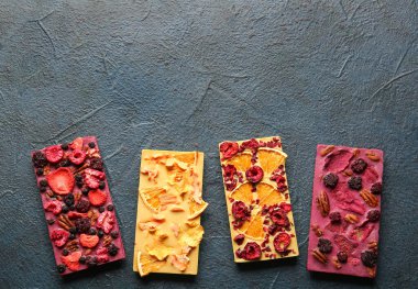 Koyu arkaplanda meyveli, meyveli ve fındıklı el yapımı çikolatalar.