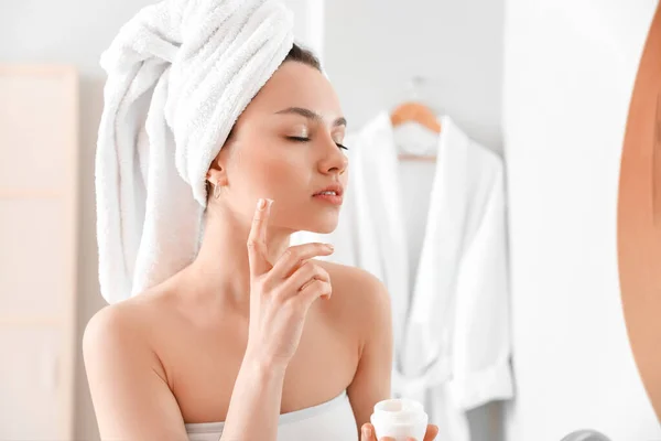 Mujer Joven Aplicando Crema Facial Baño —  Fotos de Stock