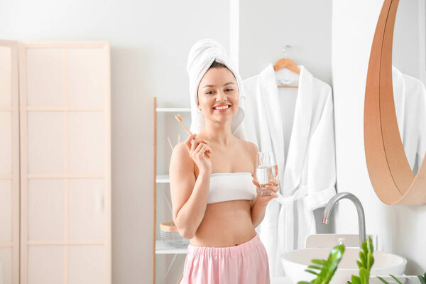 Молодая женщина чистит зубы в ванной