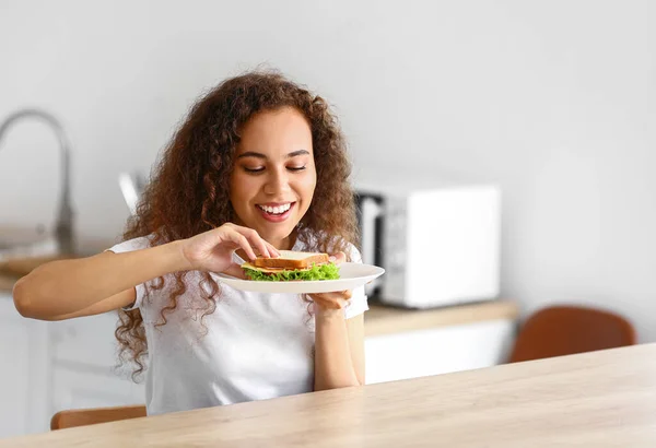 Young African American Woman Eating Tasty Sandwich Kitchen — Stock Photo, Image