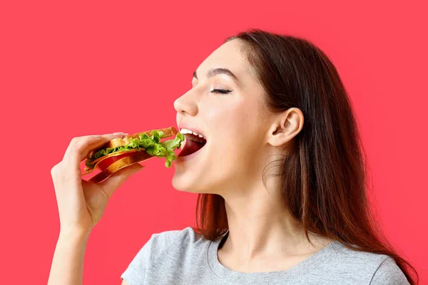 Jonge Vrouw Eten Smakelijke Sandwich Kleur Achtergrond — Stockfoto
