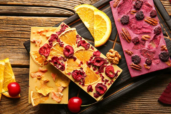 Ahşap arka planda meyveli, meyveli ve fındıklı el yapımı çikolatalar.