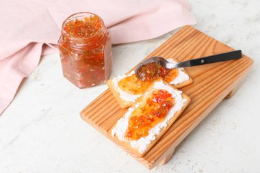 Süzme peynirli leziz krakerler ve beyaz masada biber reçeli.