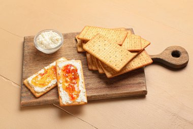 Süzme peynirli leziz krakerler ve ahşap masada biber reçeli.