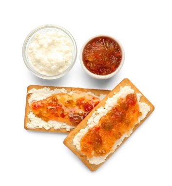 Süzme peynirli lezzetli krakerler ve beyaz arka planda jalapeno biber reçeli.