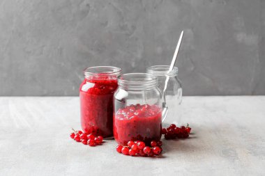 Frenk üzümü reçelli kavanozlar ve gri arkaplanda böğürtlenler