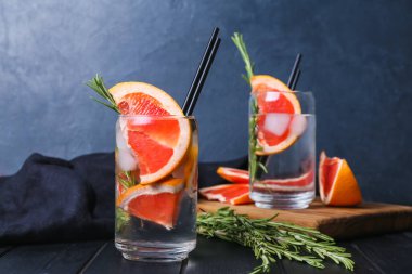 Soğuk cin tonik ve koyu ahşap arka planda greyfurt dilimleri.