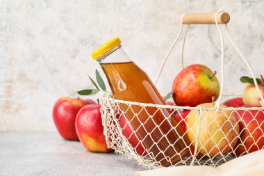 Bir sepet elma suyu ve arka planda taze meyveler.