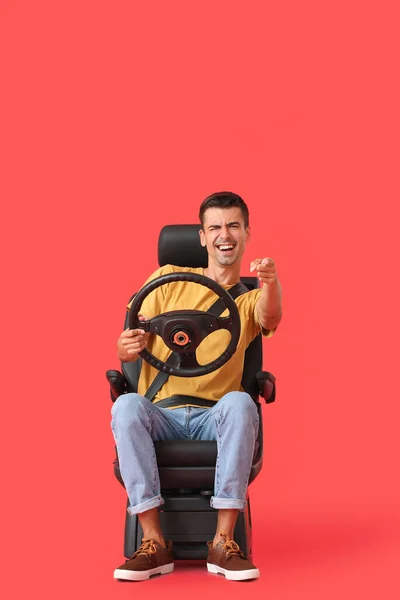 Эмоциональный Мужчина Автомобильном Кресле Рулем Указывающим Зрителя Цветном Фоне — стоковое фото