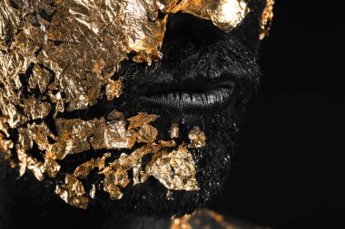 Yüzünde siyah ve altın rengi boya olan yakışıklı genç adam, yakın plan.