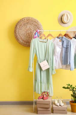 Renkli duvarın yanında şık kıyafetler, ayakkabılar ve aksesuarlarla dizilin.