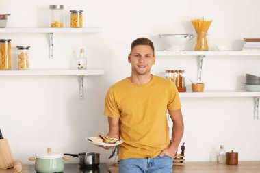 Evde lezzetli quesadilla yiyen yakışıklı genç adam.