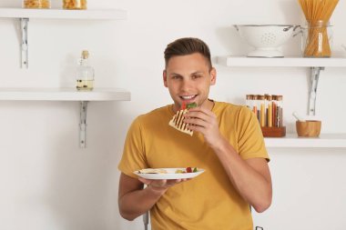 Evde lezzetli quesadilla yiyen yakışıklı genç adam.