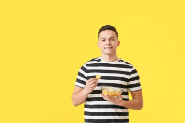 Renkli arkaplanda lezzetli cipsleri olan yakışıklı bir genç.