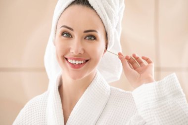 Banyoda pamuklu tomurcukla kulakları temizleyen genç bir kadın.