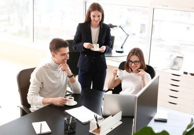 İş arkadaşları ofiste çalışırken kahve içiyorlar.