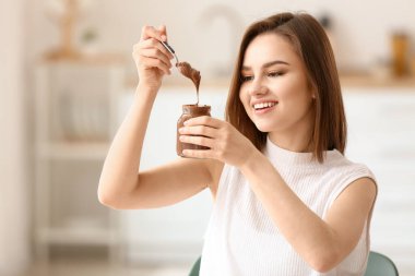 Evde lezzetli çikolata ezmesi olan güzel genç bir kadın.