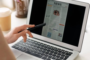 Genç bir kadın internette gazete okuyor.