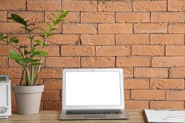 Duvarın yanında dizüstü bilgisayarı olan modern bir işyeri.