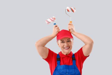 Açık arkaplanda tekerlekli fırçaları olan kadın ressam