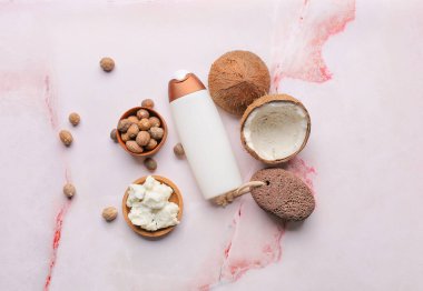 Hafif arka planda Shea yağı, fındık ve bir şişe kozmetik ürünü olan bir kase.