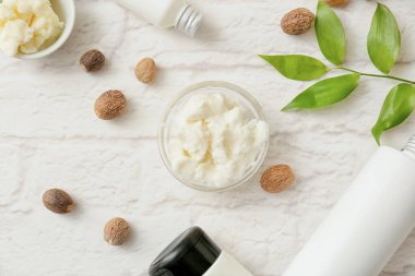 Hafif tuğlalı arka planda Shea yağı, fındık ve kozmetik ürünleri içeren kompozisyon, yakın plan