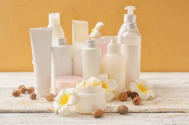 Shea yağı kavanozu ve ahşap masada farklı kozmetik ürünleri.