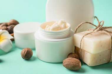 Renkli arka planda bir kavanoz Shea yağı, fındık ve kozmetik ürünleri, yakın plan