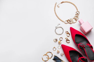 Beyaz arka planda kadın aksesuar, ayakkabı ve parfüm seti, yakın plan.